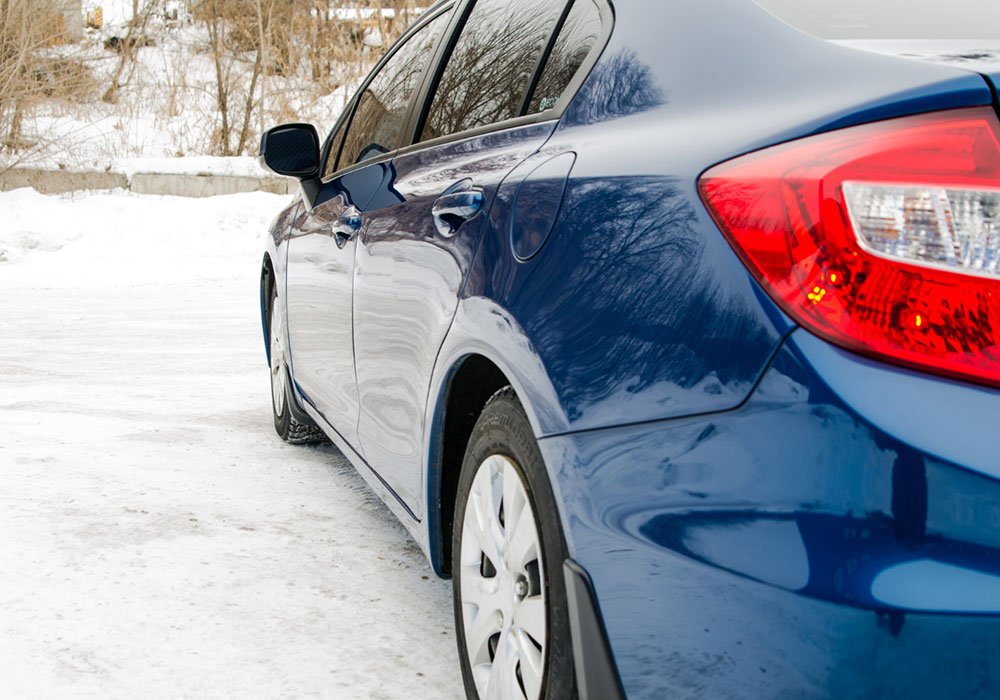 A car in snow, awaiting a winter check.